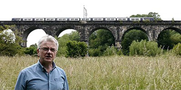 Man talking to the camera by a railway viaduct