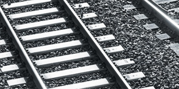 Black and white close-up of railway tracks resting on a bed of grey gravel ballast